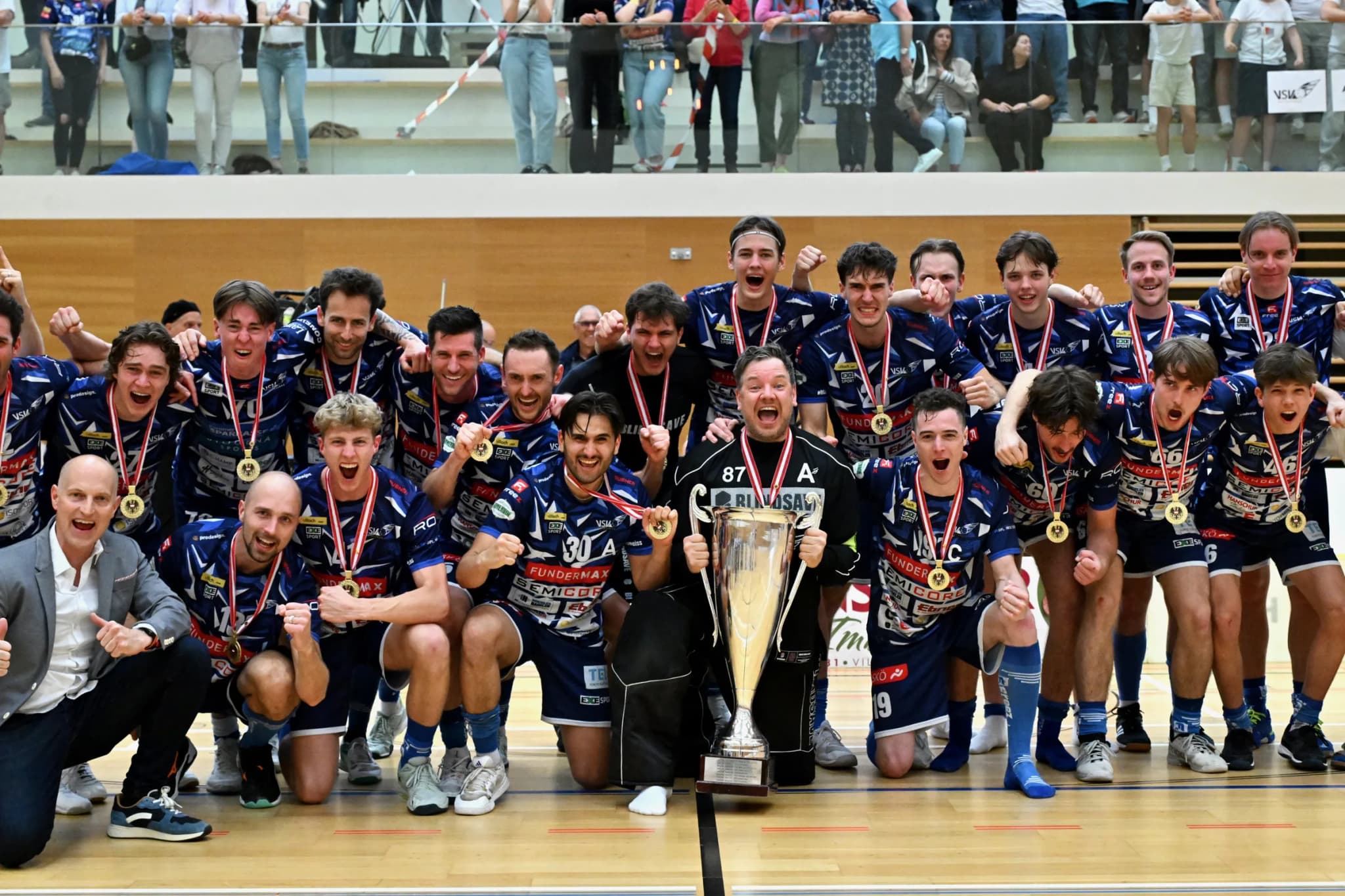 Mannschaftsfoto mit Meisterpokal und Medaillen vor voller Tribüne